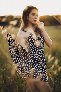 A woman wearing a flowing bohemian dress standing in a sunlit field with wildflowers.