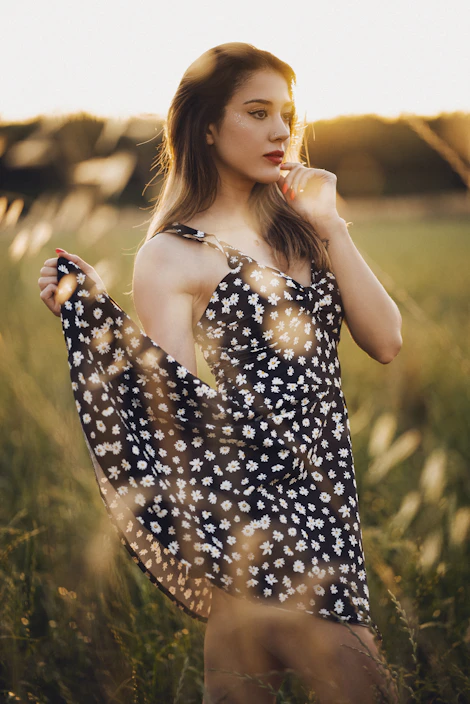 A chic bohemian woman wearing a flowing dress from the 'les imparfaites' collection, standing in a sunlit field.