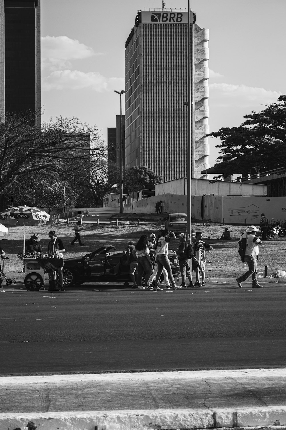 um grupo de pessoas caminhando por uma rua ao lado de um prédio alto