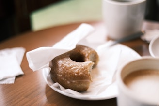 A sasquatch-shaped donut with chocolate glaze and powdered sugar footprints on a wooden picnic table