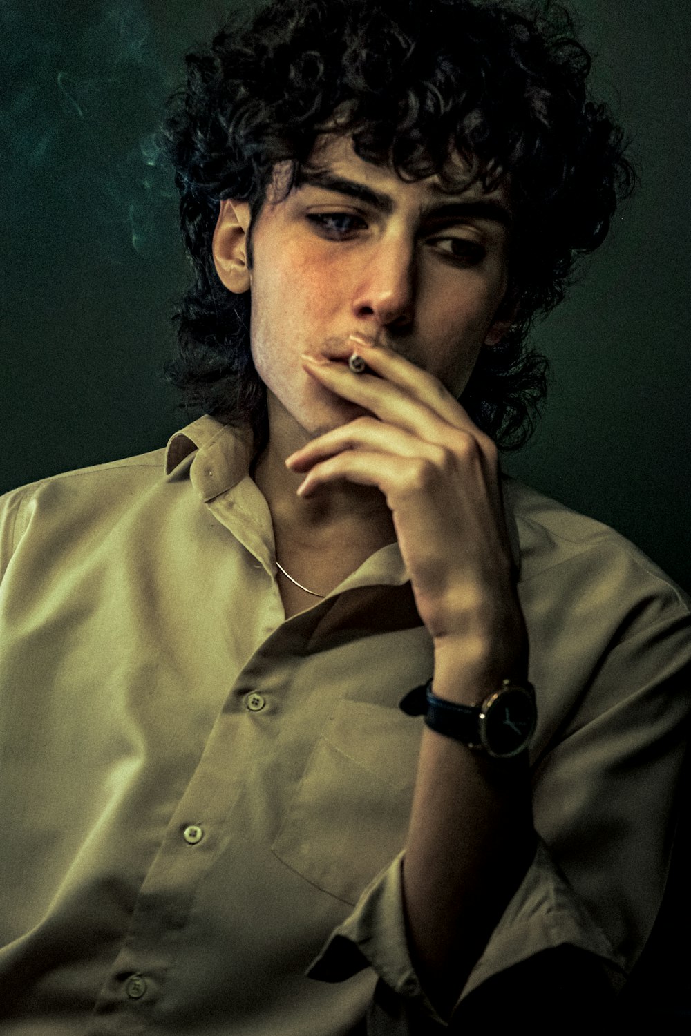a man with curly hair smoking a cigarette