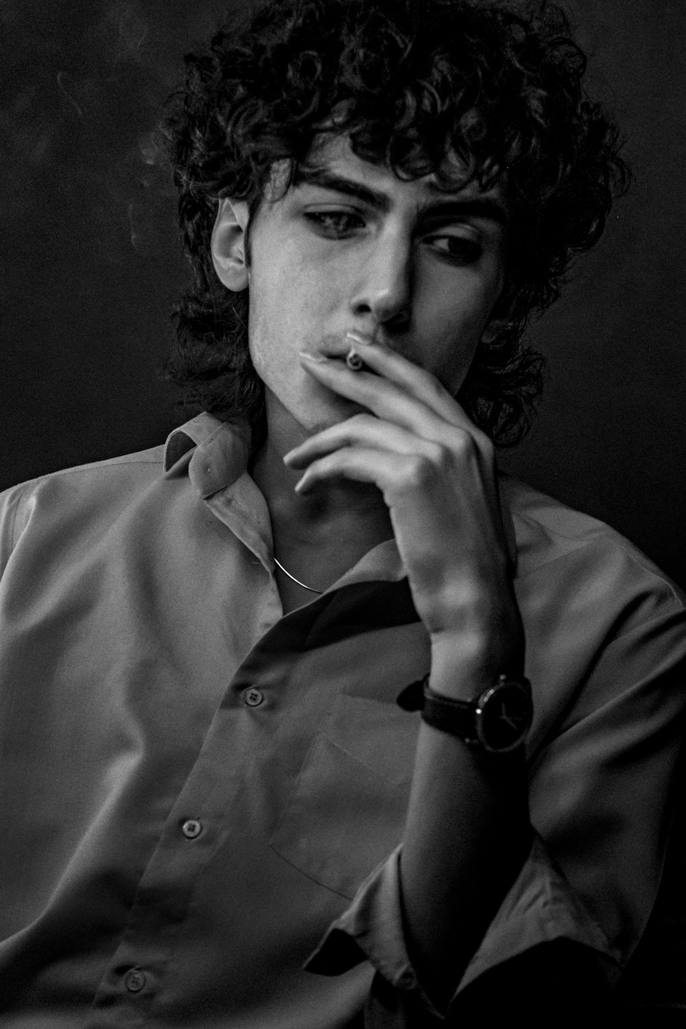 a man with curly hair smoking a cigarette