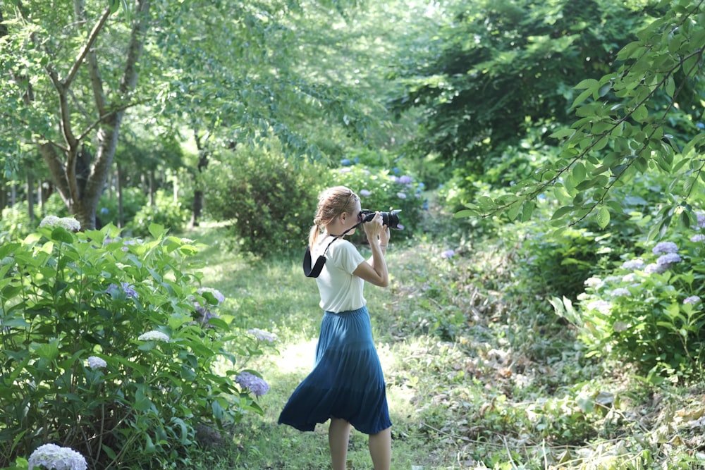 a woman is taking a picture of flowers in the woods