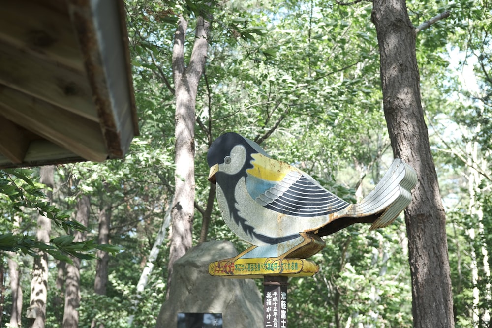 a bird statue sitting on top of a wooden pole