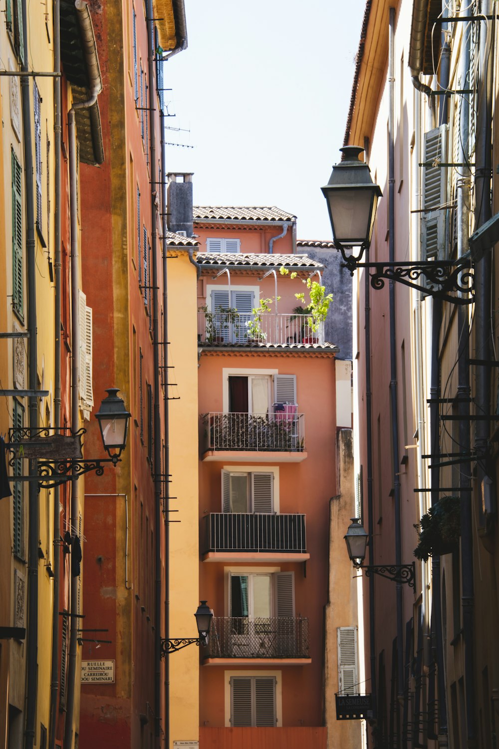 a narrow alleyway with a lamp post and balconies