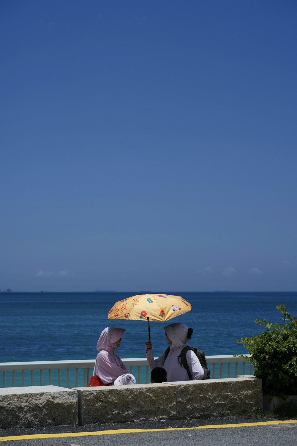 a couple of women sitting on top of a bench under an umbrella