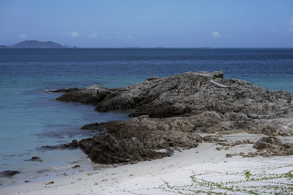 a rocky outcropping on a beach next to the ocean