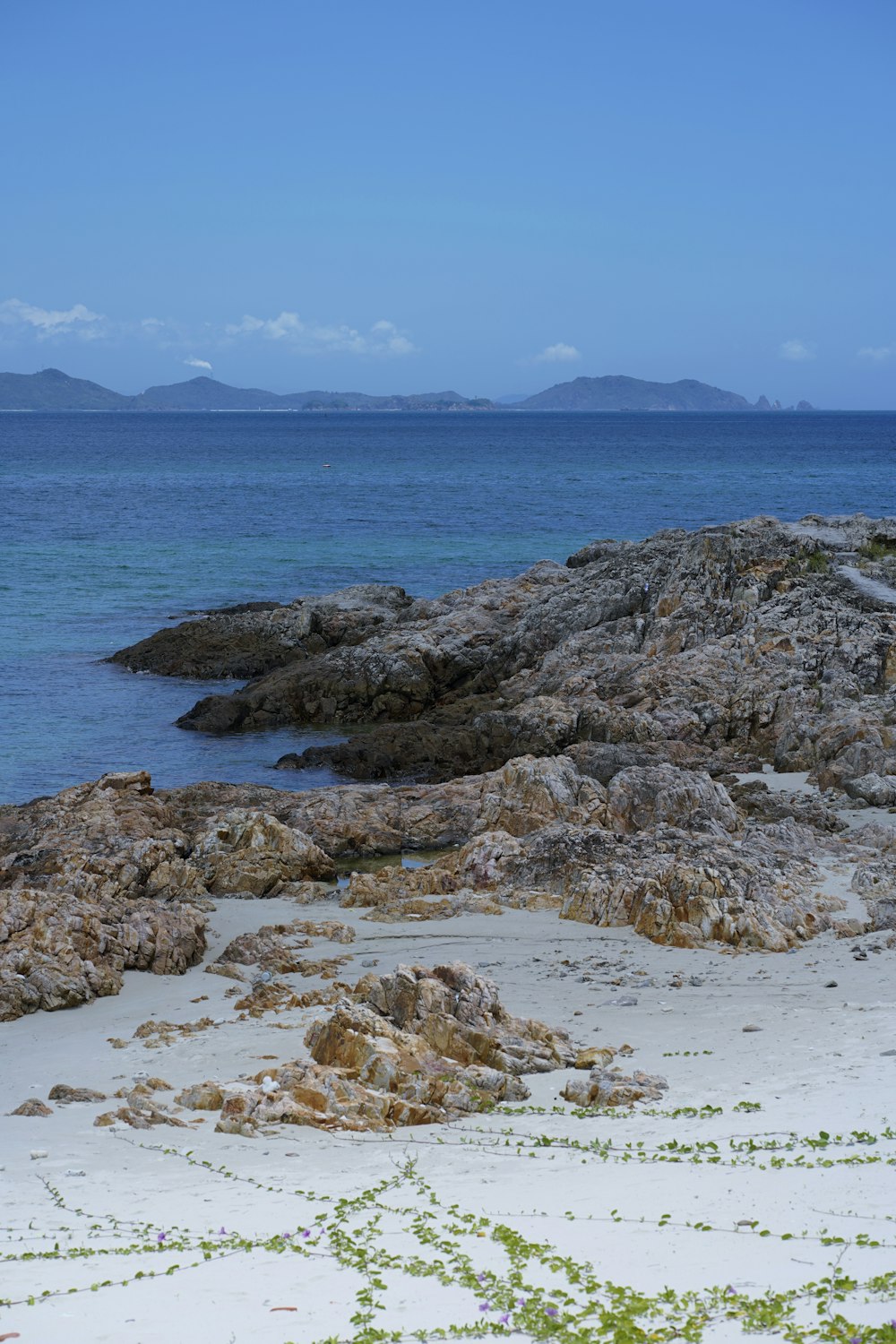 a couple of rocks sitting on top of a sandy beach