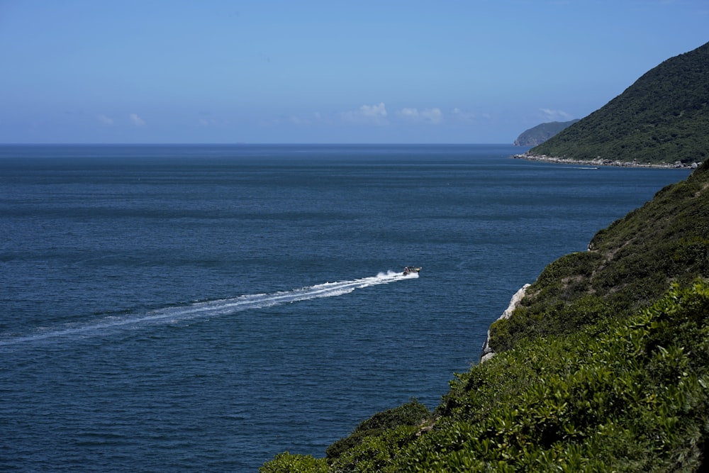 a boat traveling on the ocean near a cliff