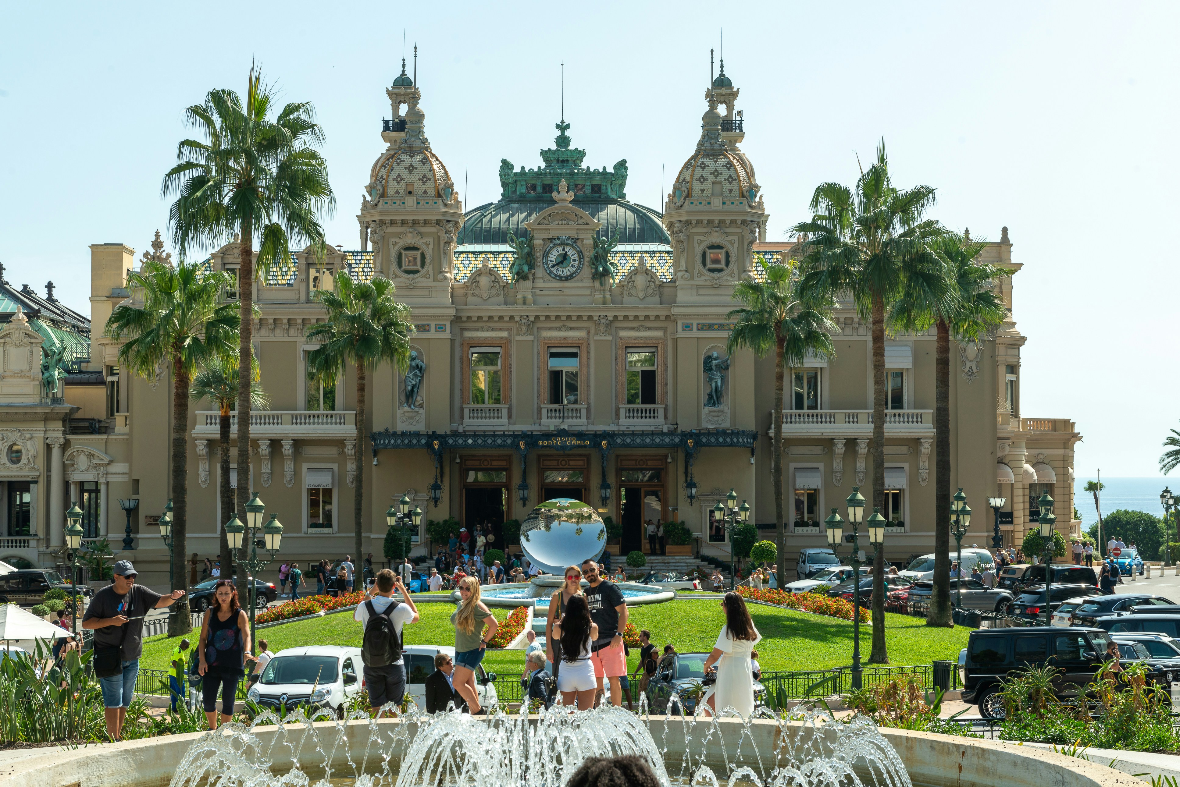 a group of people standing around a fountain in front of a building