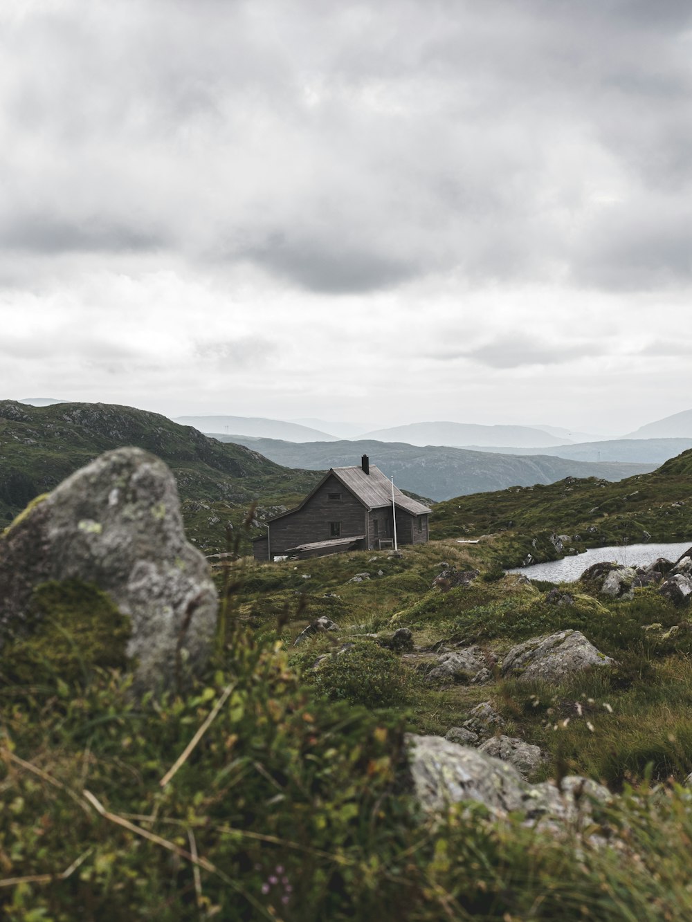 a house in the middle of a field with mountains in the background