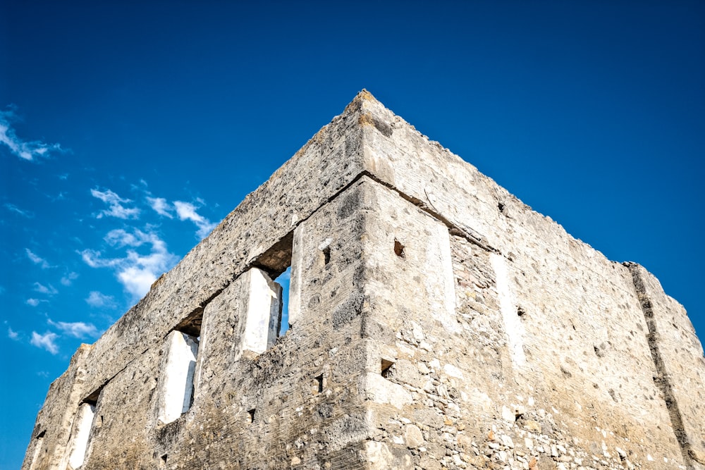 a stone building with two windows and a sky background