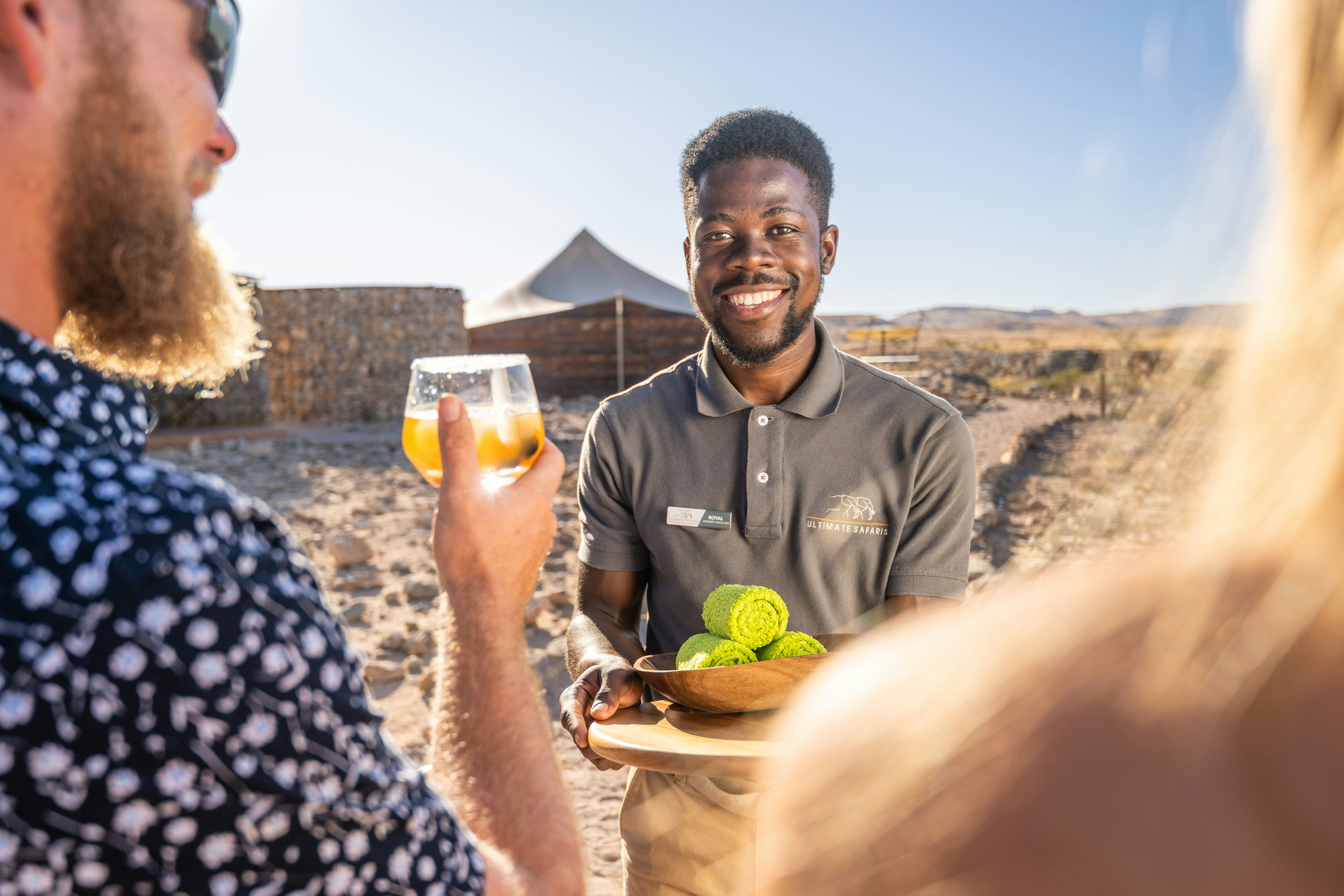 a man holding a plate of food and a glass of beer, Camp Doros, Ultimate Safaris, Namibia