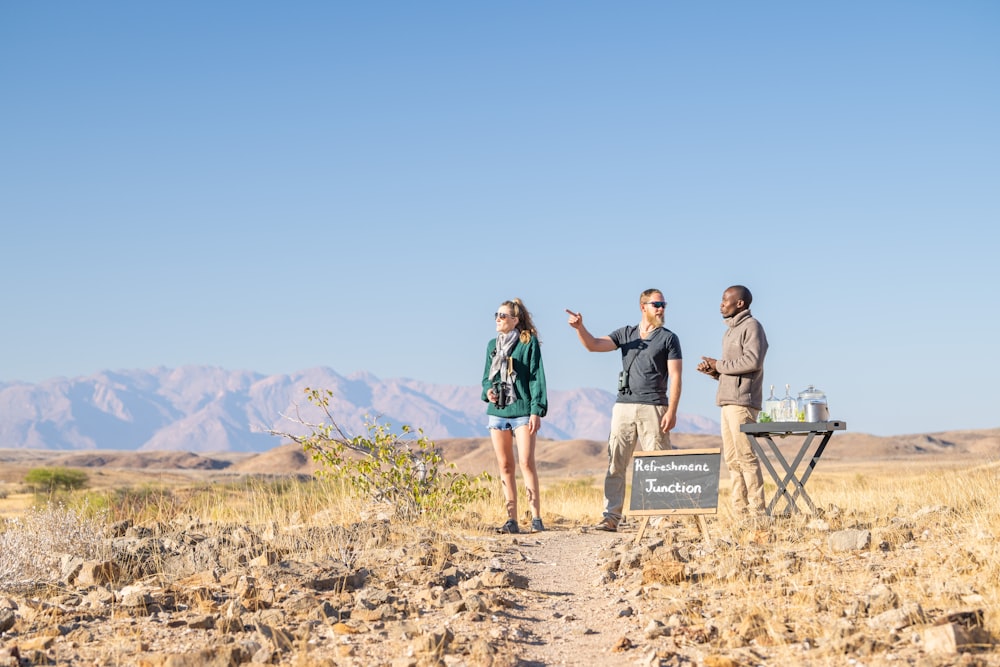 a group of people standing on top of a dirt field