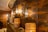 A warm, rustic setting featuring a textured brown wall with woven basket-like light fixtures and hanging lanterns. The ambient lighting creates a cozy and inviting atmosphere, enhancing the earthy tones of the decor.
