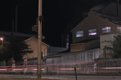 Nighttime exterior shot of a factory with visible security cameras and lighting