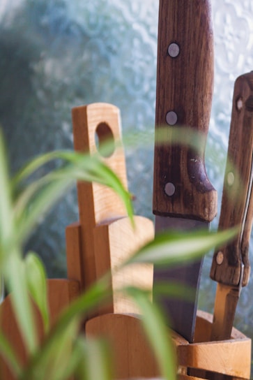 A close-up of a set of kitchen knives with wooden handles on a rustic cutting board.