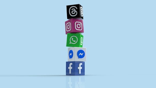 A vertical stack of colorful cubes, each displaying a logo of different social media platforms including Facebook, Messenger, WhatsApp, Instagram, and Threads, placed against a light blue background.