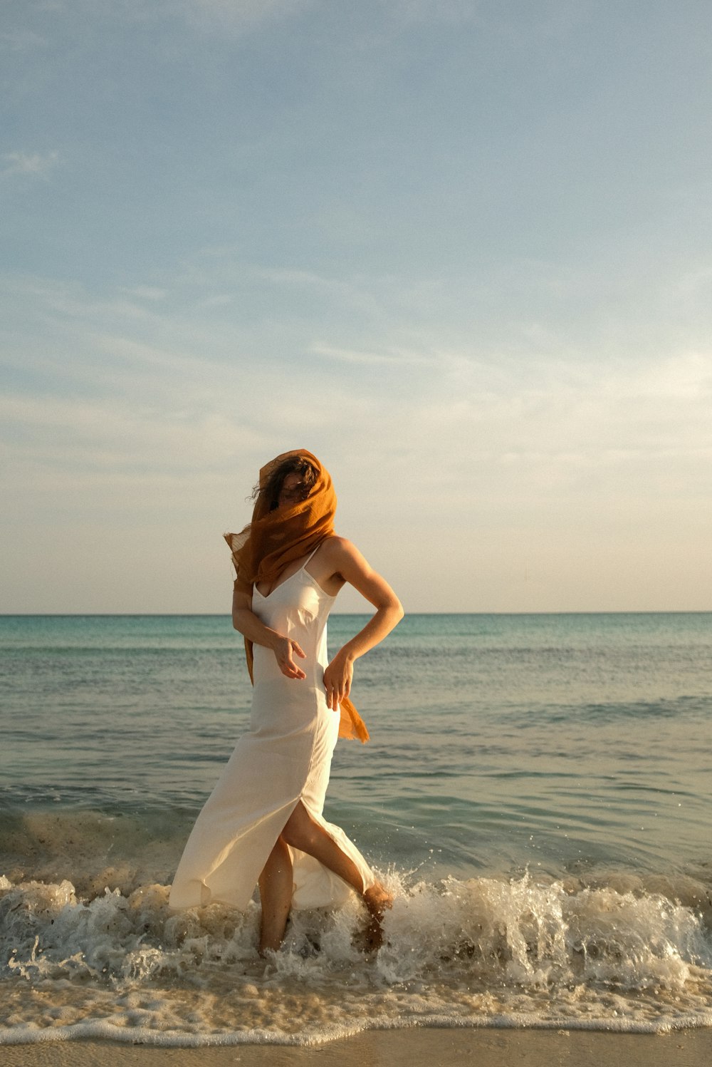 a woman in a white dress is walking on the beach