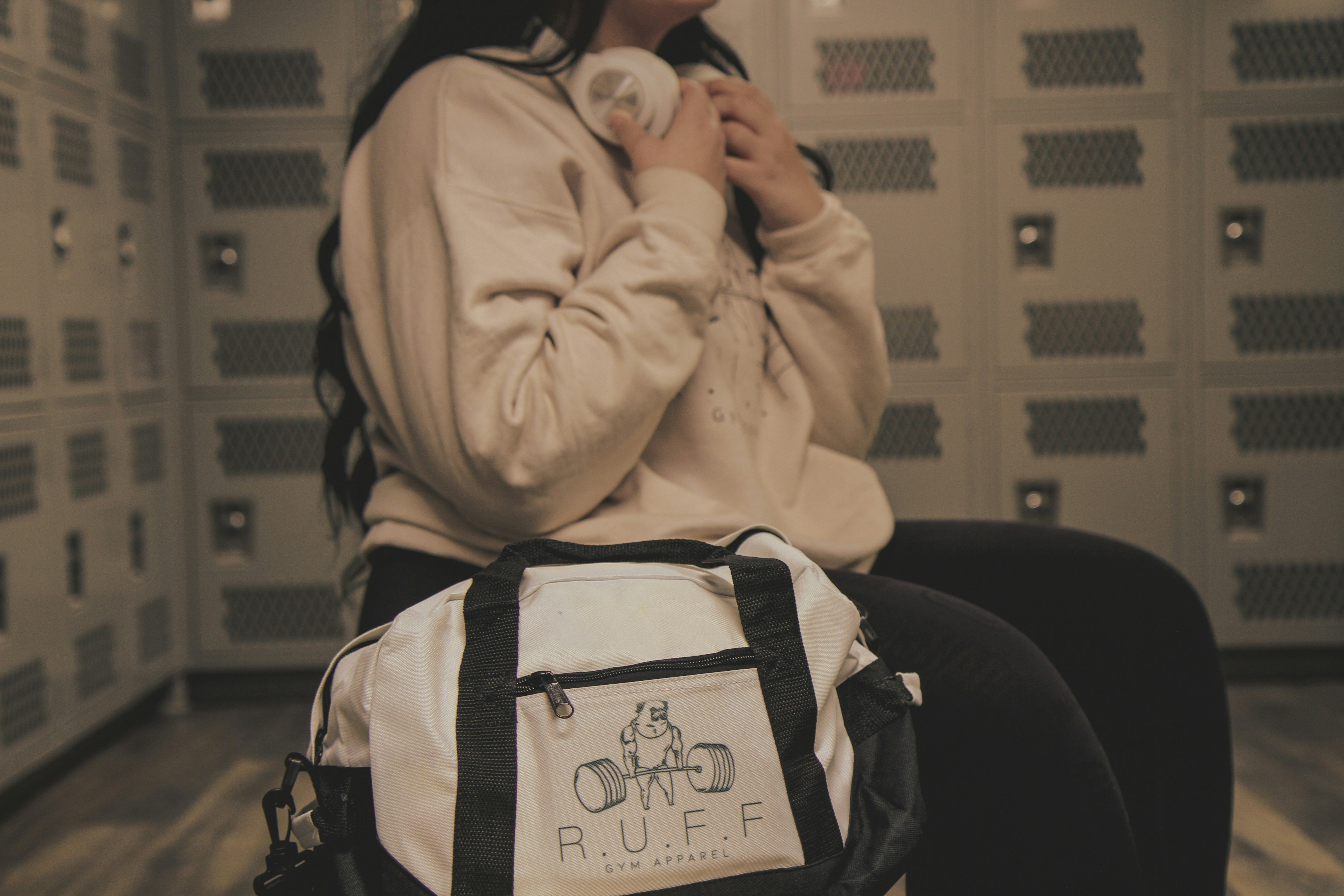 a woman sitting in a locker with a duffle bag
