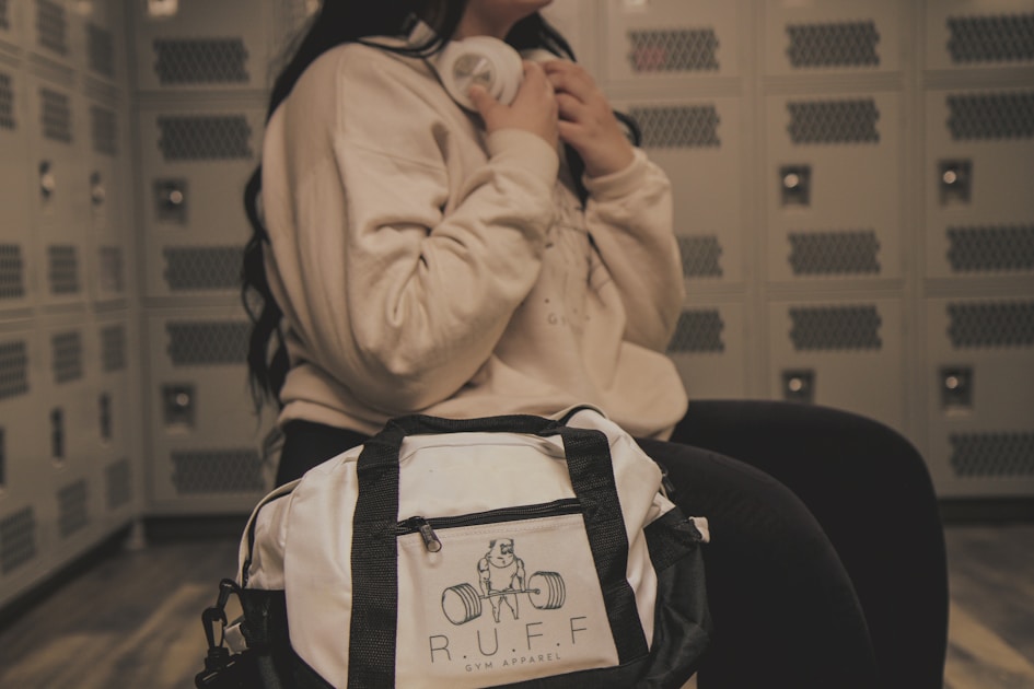 Athlete in a locker room pulling a change of clothes from a canvas duffel bag