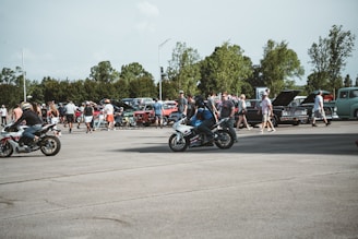 A dynamic shot of a group of riders gathered around custom bikes at an outdoor event under overcast skies.