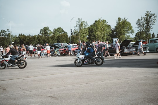A dynamic shot of a group of riders gathered around custom bikes at an outdoor event under overcast skies.