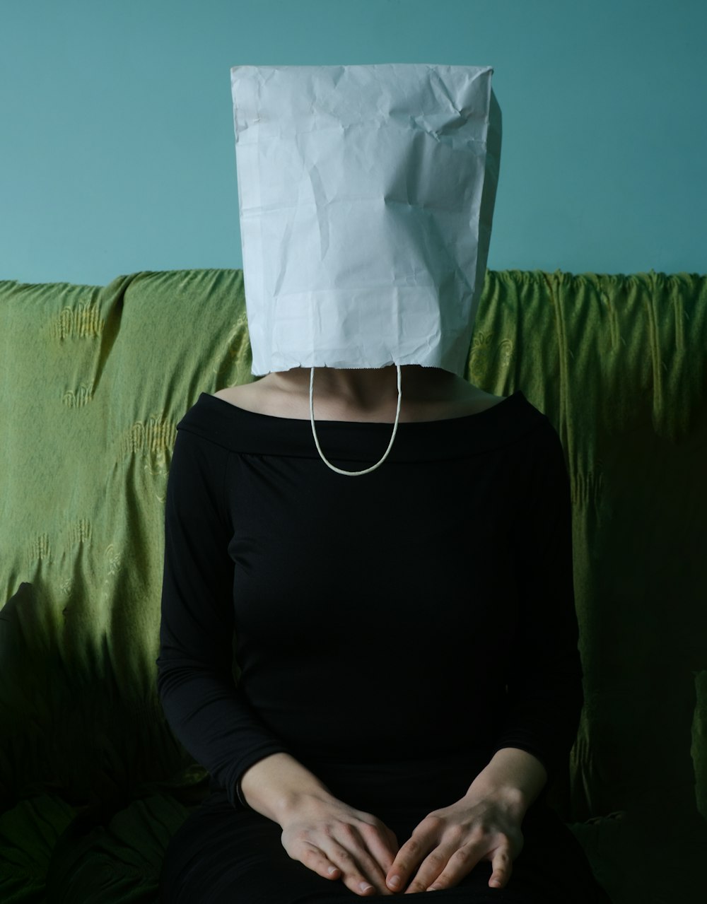 une femme assise sur un canapé avec un sac en papier sur la tête