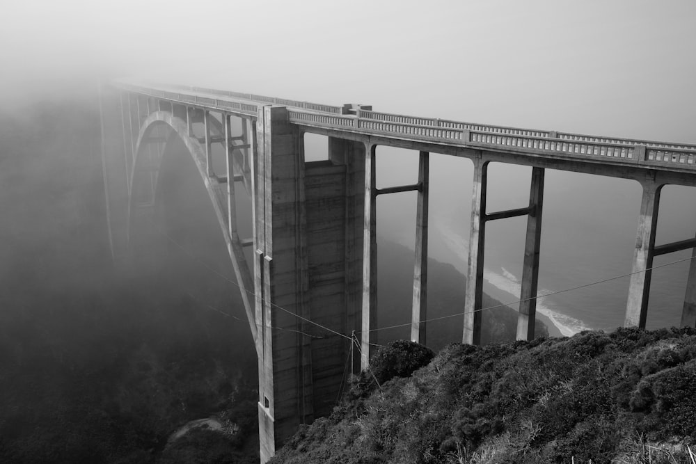 a black and white photo of a bridge on a foggy day
