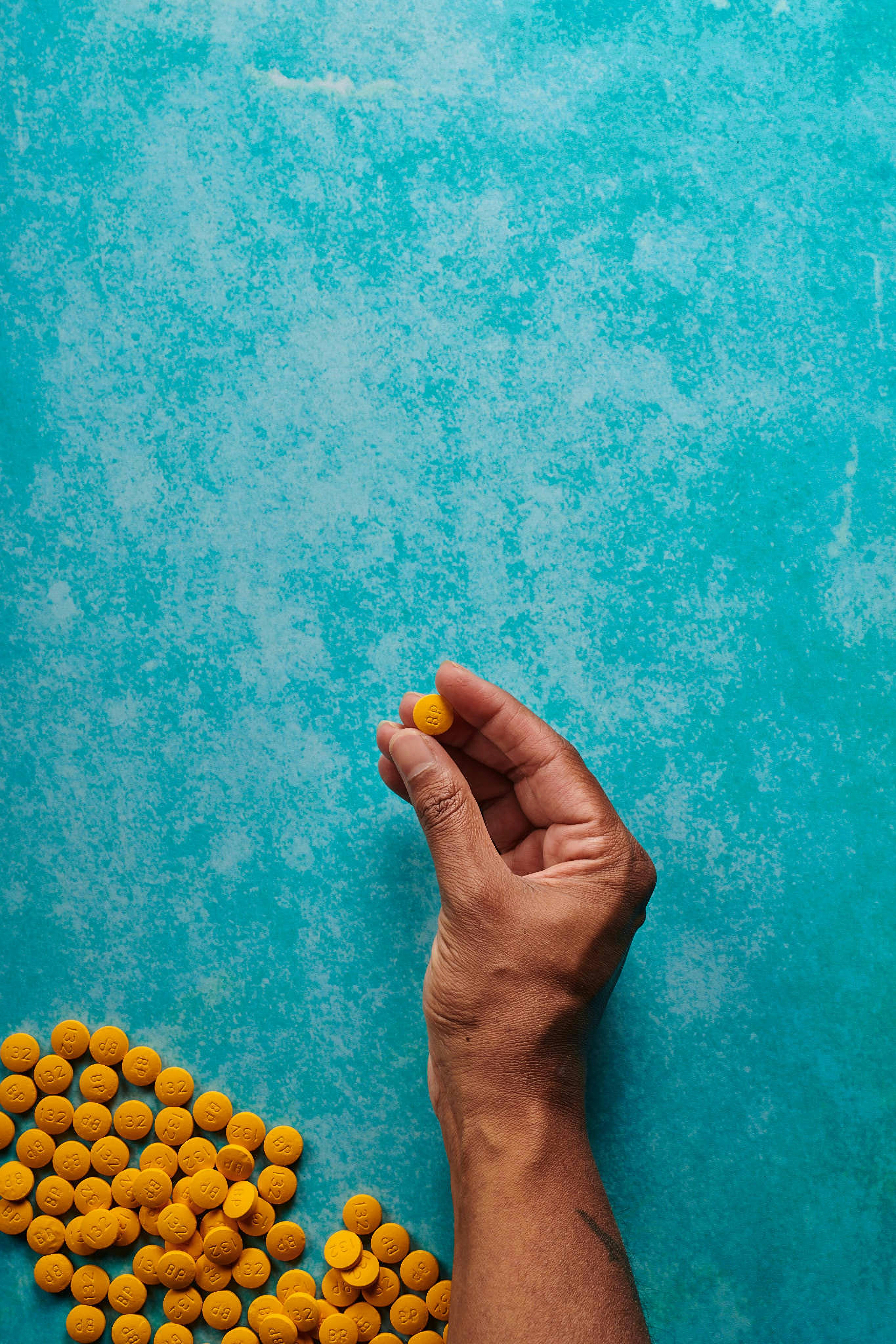 a hand reaching up towards a pile of yellow candies
