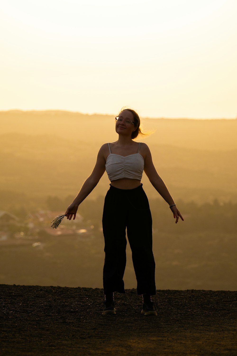 a woman standing on top of a hill with her arms outstretched