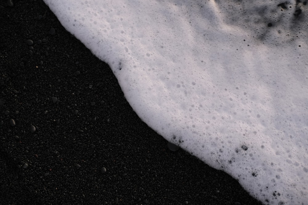 a black sand beach with white foam on it