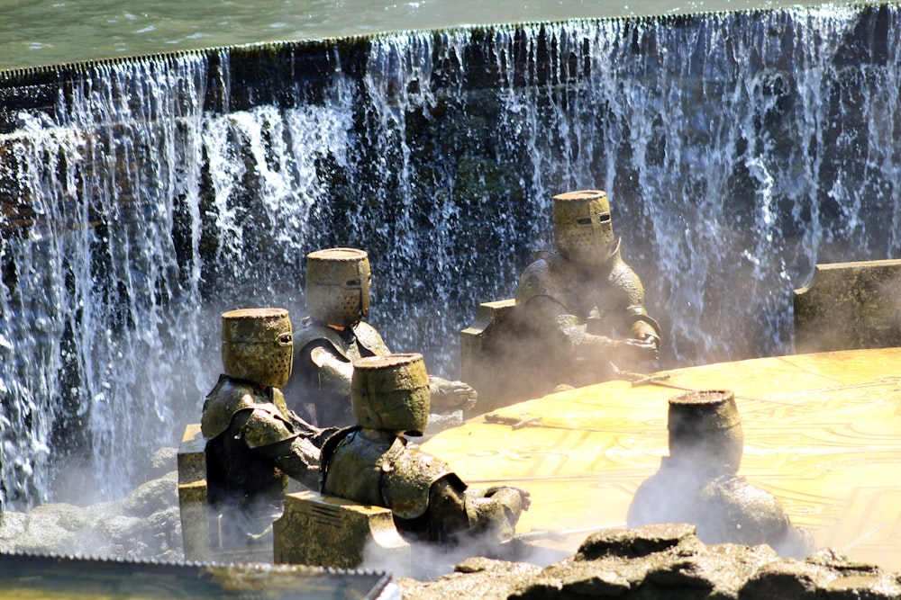 a group of statues sitting in front of a waterfall