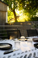 A vibrant table setting outdoors with colorful patterned tablecloths catching the sunlight.