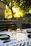 A sunlit picnic table set with crisp white napkins and green leafy decorations.