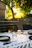 A sunlit picnic table set with crisp white napkins and green leafy decorations.