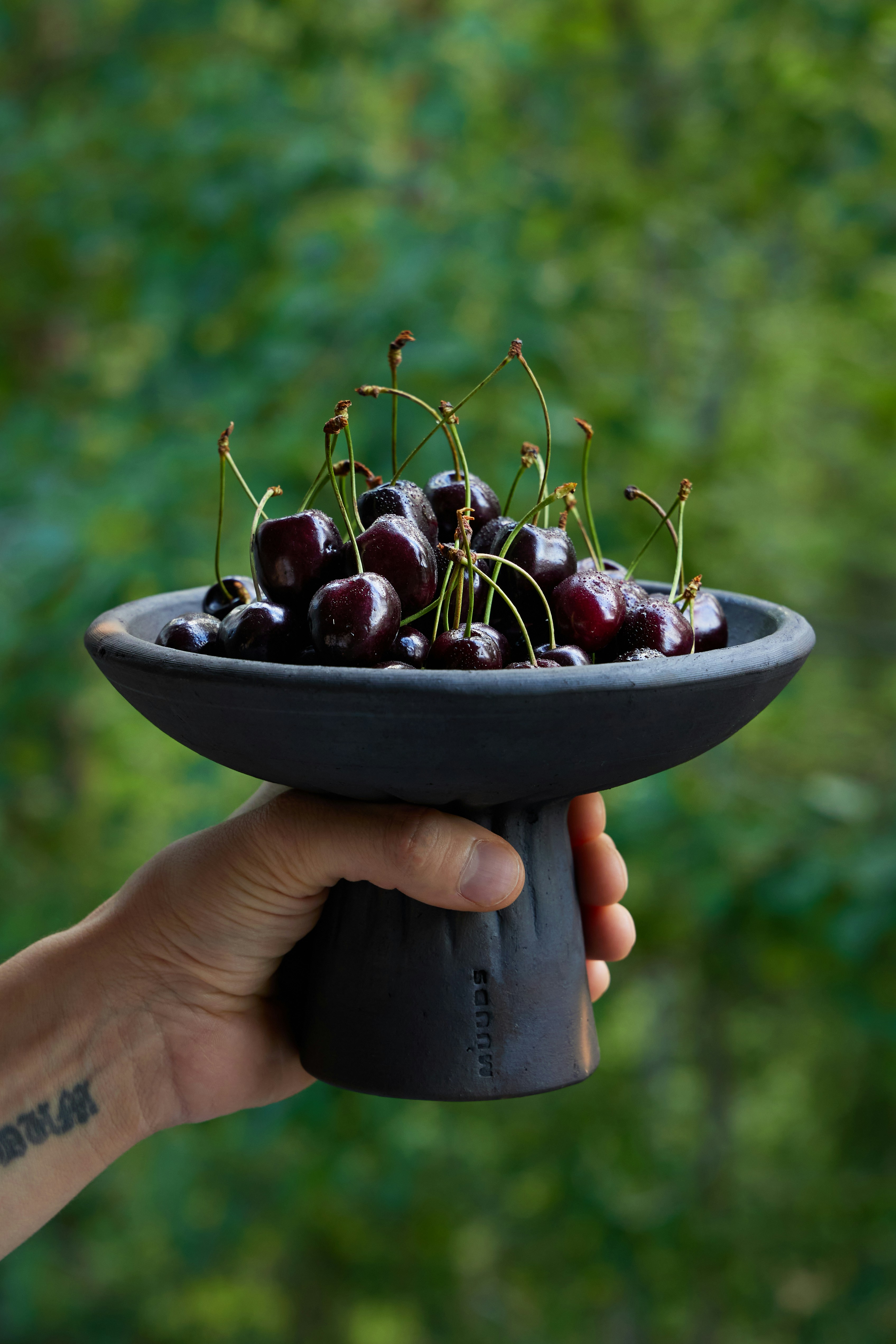 uma pessoa segurando uma tigela preta cheia de cerejas