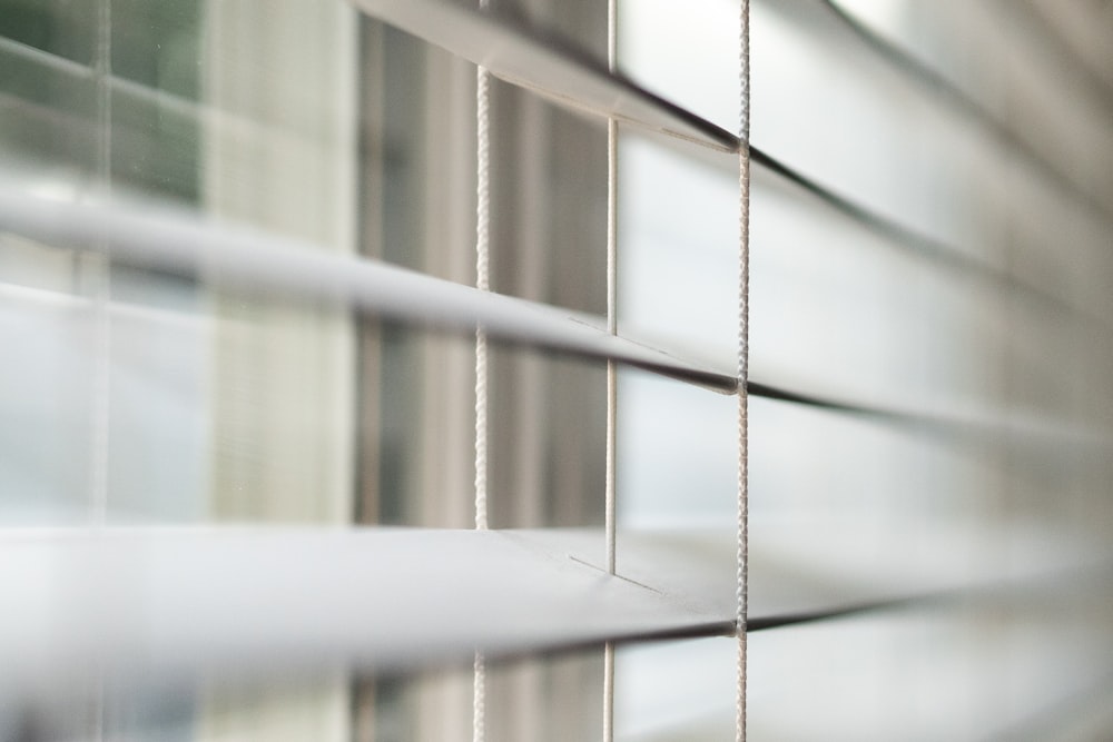 a close up of a window with white blinds