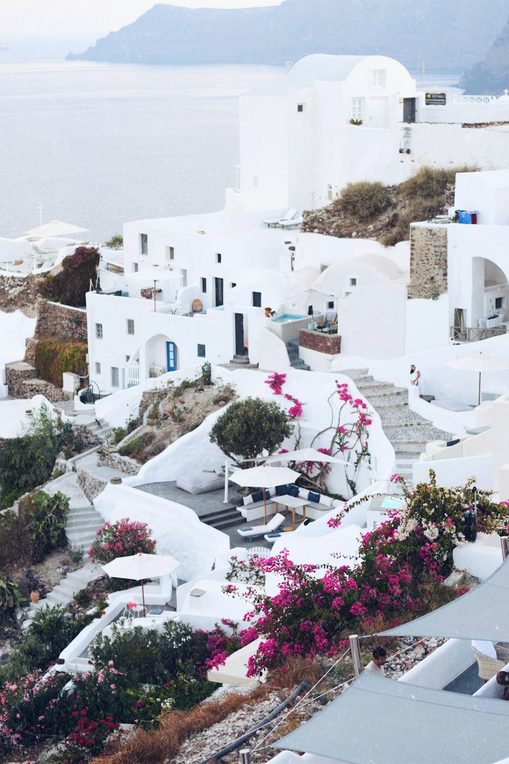 an aerial view of a white village with pink flowers