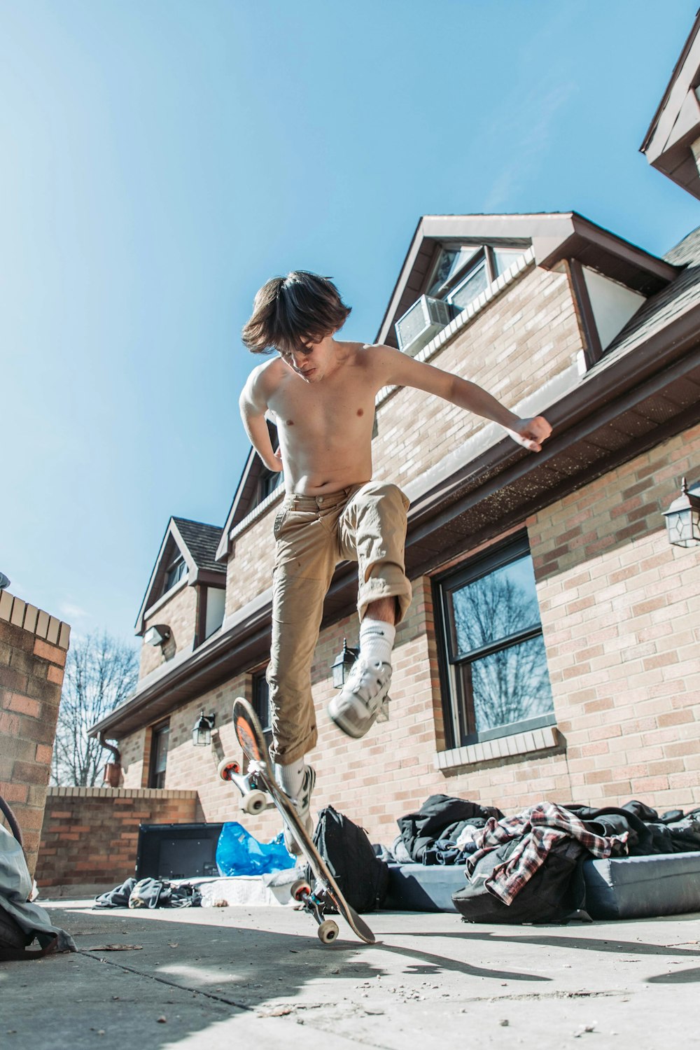 ein hemdloser Skateboarder, der vor einem Haus einen Trick macht