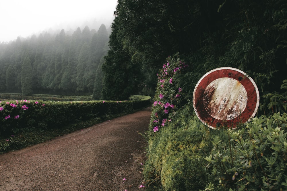 a red and white sign sitting on the side of a dirt road