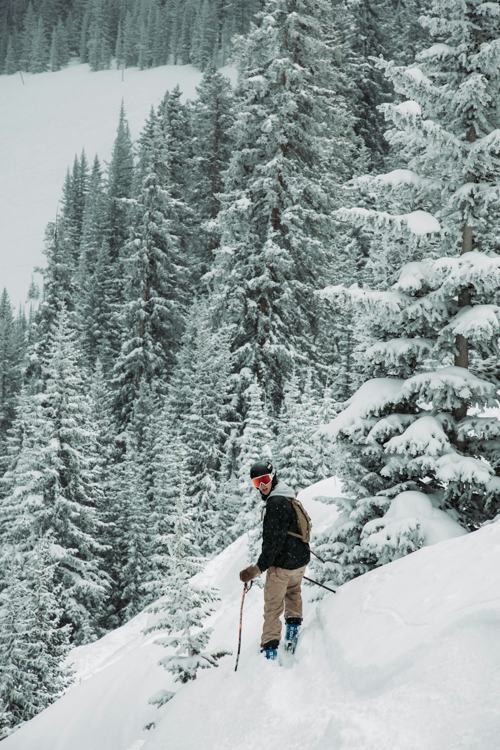 눈 덮인 언덕에 서 있는 스키를 탄 사람