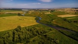 Aerial shot of a lush green Normandy countryside with winding rivers under a clear blue sky.