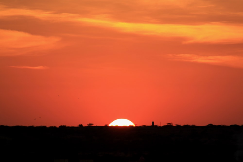 the sun is setting over the horizon of a field