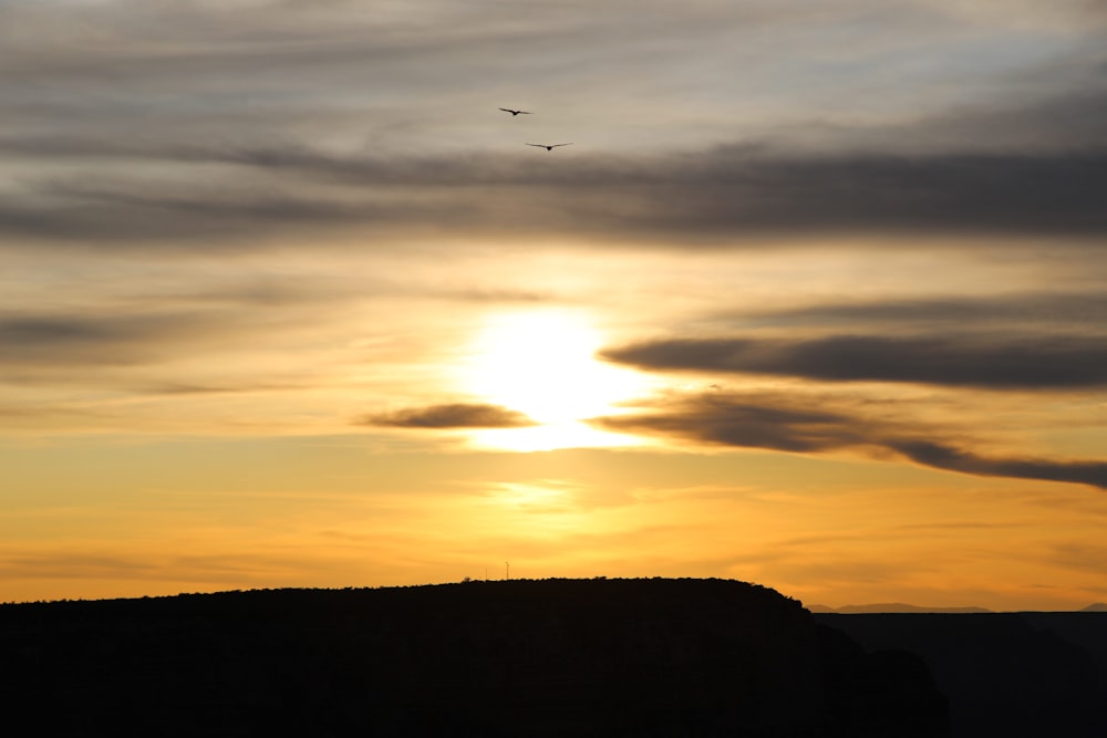 a plane flying in the sky at sunset