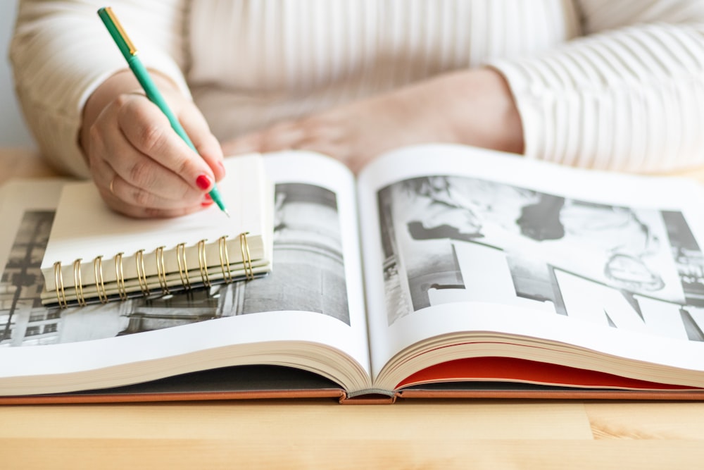 a person holding a pen and writing on a book