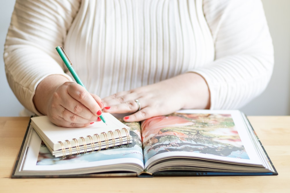 a woman is holding a pen and writing on a book