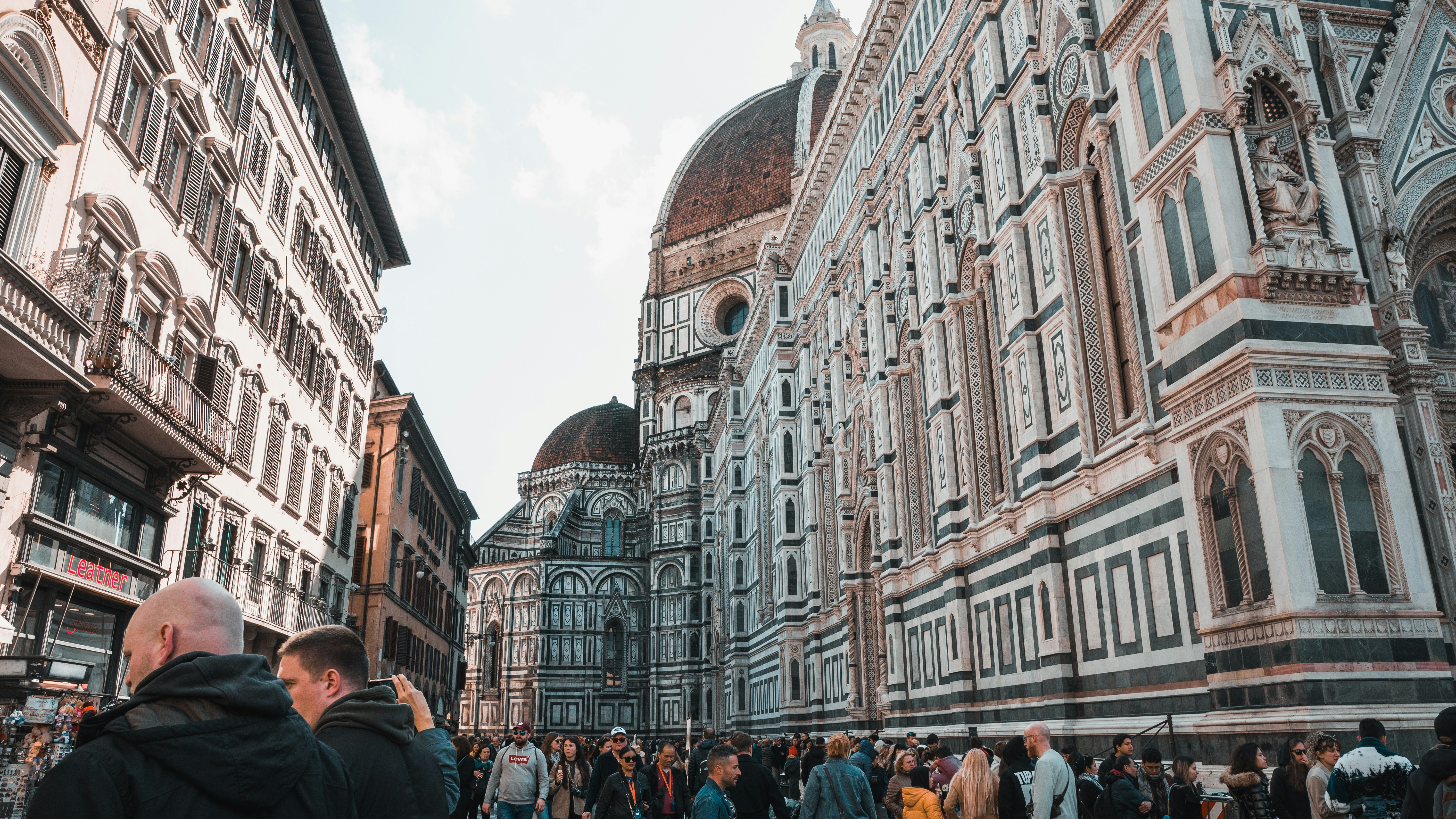 a group of people walking down a street next to tall buildings