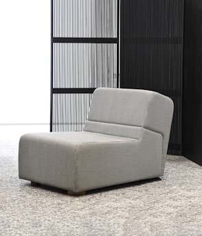 a gray chair sitting in front of a black wall