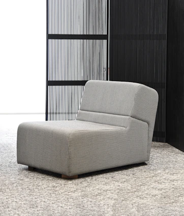 A stylish lounge chair with dark charcoal cushions in a minimalist living room
